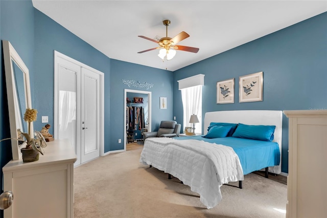 bedroom featuring a closet, a spacious closet, light carpet, ceiling fan, and baseboards