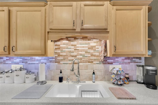 kitchen featuring light brown cabinets, decorative backsplash, light countertops, and a sink