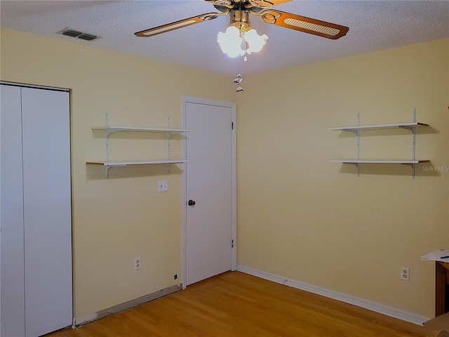 unfurnished bedroom with a closet, ceiling fan, light hardwood / wood-style floors, and a textured ceiling