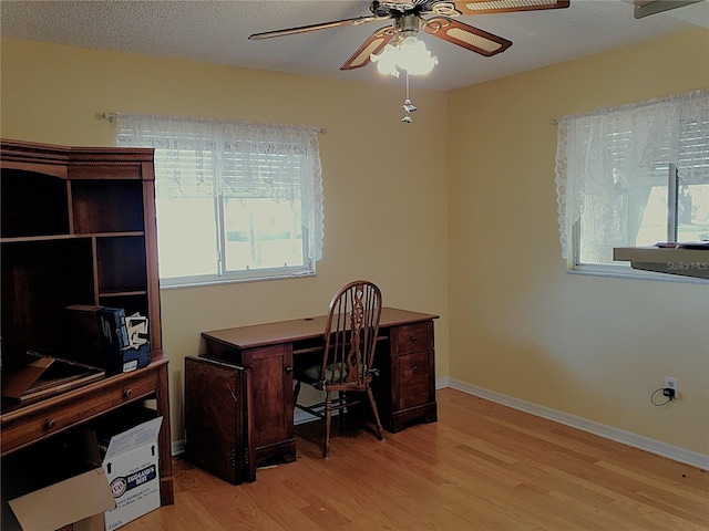 office area featuring ceiling fan, a wealth of natural light, a textured ceiling, and light hardwood / wood-style floors