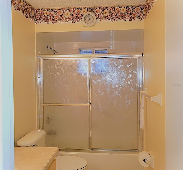 full bathroom featuring vanity, shower / bath combination with glass door, and toilet