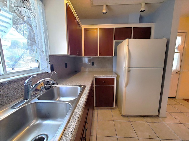 kitchen with white refrigerator, light tile patterned flooring, and sink