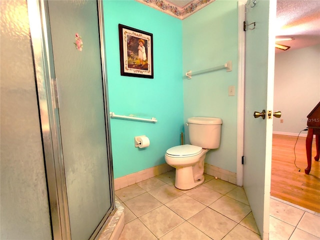 bathroom with toilet, a shower with shower door, and tile patterned flooring