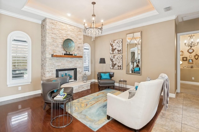 living room with crown molding, plenty of natural light, a chandelier, and a fireplace