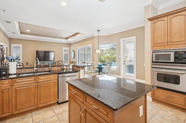 kitchen with sink, decorative light fixtures, dark stone countertops, appliances with stainless steel finishes, and a kitchen island