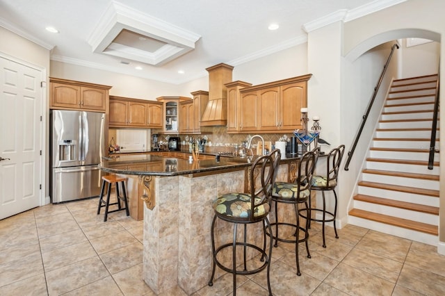 kitchen with a kitchen bar, stainless steel fridge, light tile patterned floors, and dark stone countertops