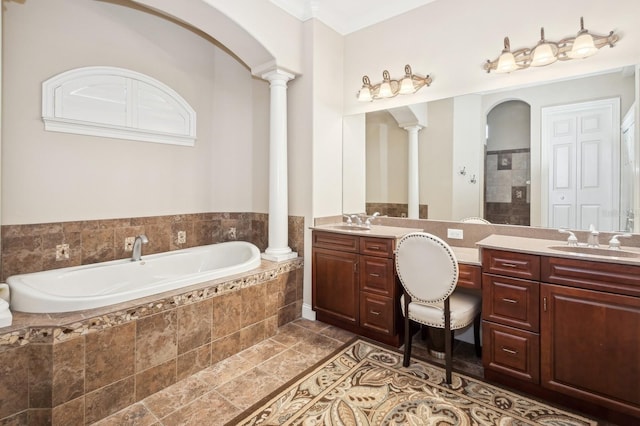 bathroom with decorative columns, vanity, tiled tub, and tile patterned floors