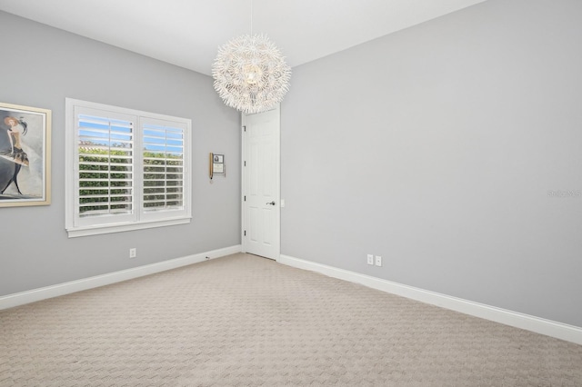 carpeted spare room with an inviting chandelier