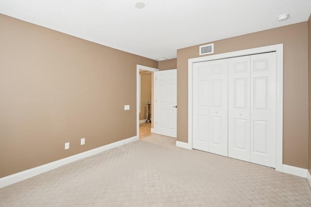 unfurnished bedroom with light colored carpet and a closet