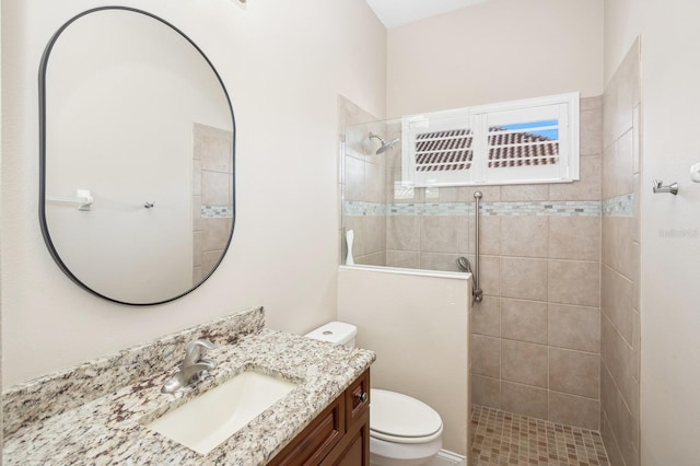 bathroom with vanity, tiled shower, and toilet