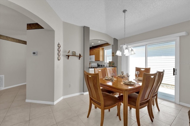 dining area with an inviting chandelier, light tile patterned floors, vaulted ceiling, and a textured ceiling