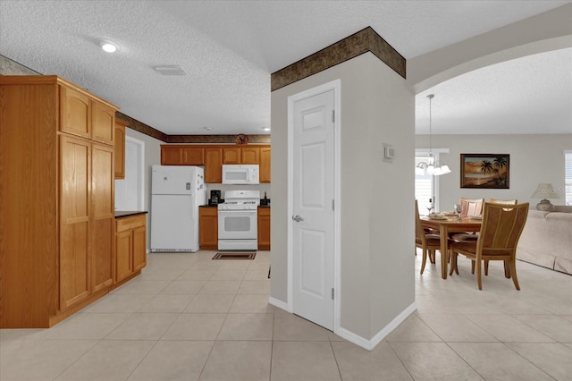 kitchen featuring pendant lighting, light tile patterned floors, white appliances, and a textured ceiling