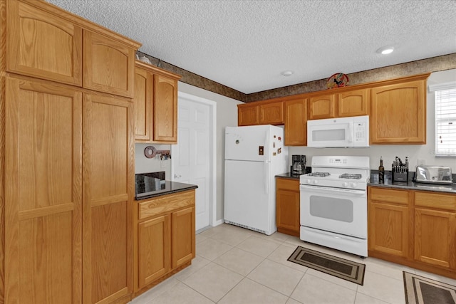 kitchen with light tile patterned flooring, white appliances, and a textured ceiling