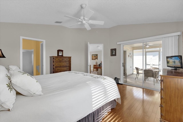 bedroom with lofted ceiling, hardwood / wood-style flooring, ceiling fan, a textured ceiling, and access to outside