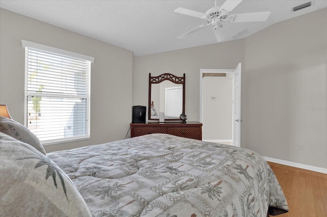 bedroom featuring ceiling fan, wood-type flooring, vaulted ceiling, and a textured ceiling