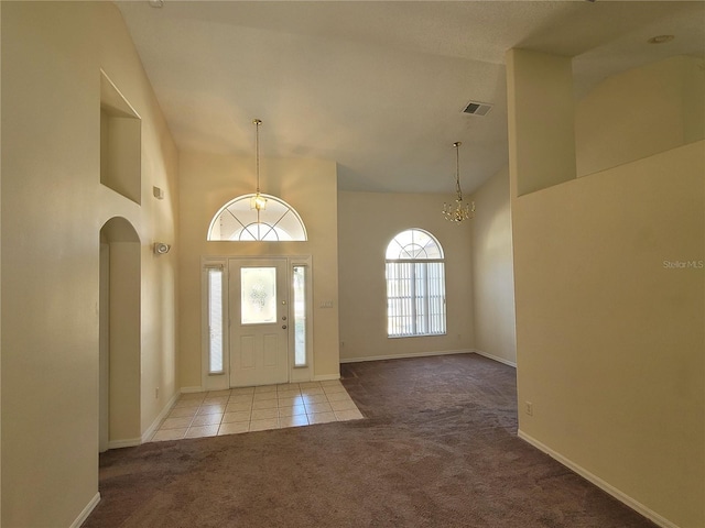 carpeted entrance foyer with a notable chandelier and high vaulted ceiling