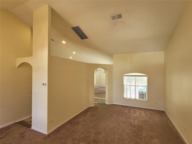 spare room featuring lofted ceiling and dark carpet