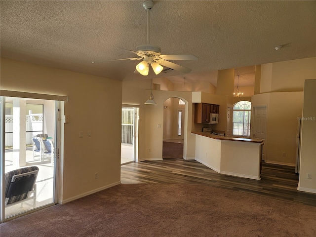 kitchen with lofted ceiling, hanging light fixtures, a textured ceiling, dark carpet, and ceiling fan