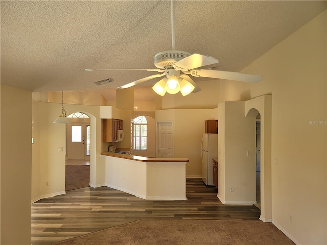 kitchen featuring ceiling fan, dark hardwood / wood-style floors, white refrigerator, a textured ceiling, and kitchen peninsula