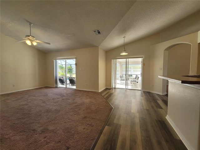 unfurnished living room featuring ceiling fan, lofted ceiling, dark wood-type flooring, and a textured ceiling