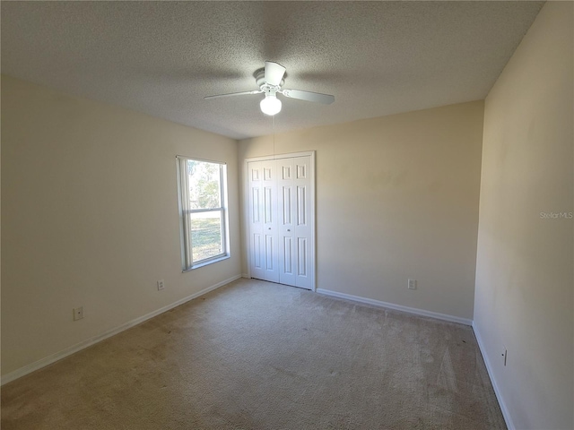 unfurnished bedroom with ceiling fan, light colored carpet, a closet, and a textured ceiling