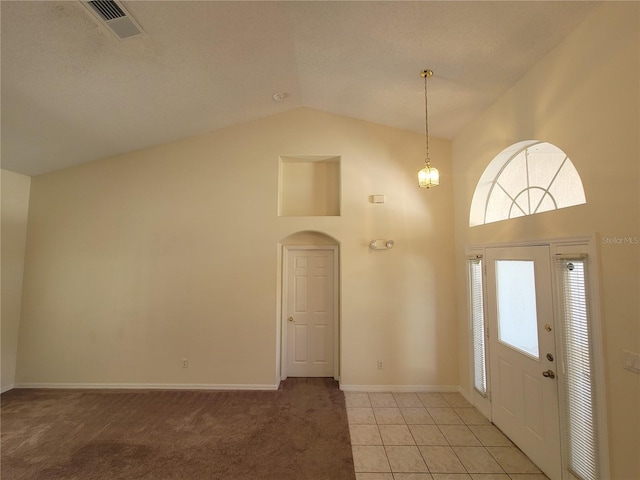 carpeted foyer entrance featuring high vaulted ceiling