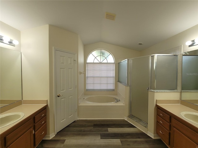 bathroom with wood-type flooring, shower with separate bathtub, vaulted ceiling, and vanity