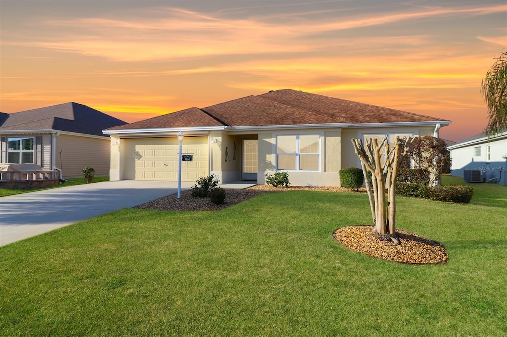 view of front facade featuring cooling unit, a garage, and a yard