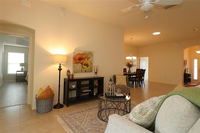 tiled living room featuring ceiling fan with notable chandelier