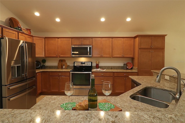 kitchen with light stone counters, sink, and appliances with stainless steel finishes