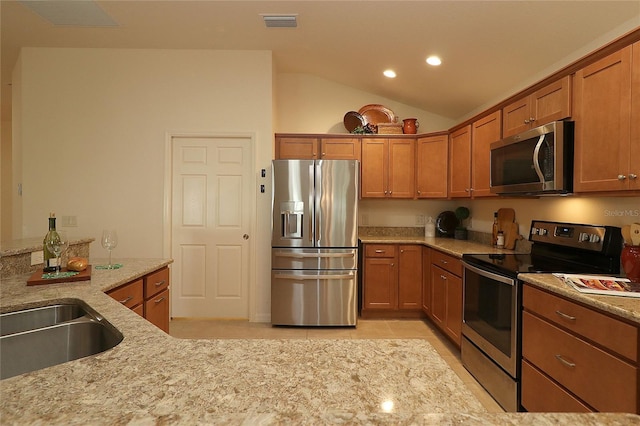 kitchen featuring vaulted ceiling, light tile patterned flooring, sink, stainless steel appliances, and light stone countertops