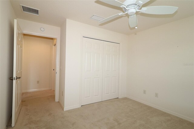 unfurnished bedroom featuring light colored carpet, a closet, and ceiling fan