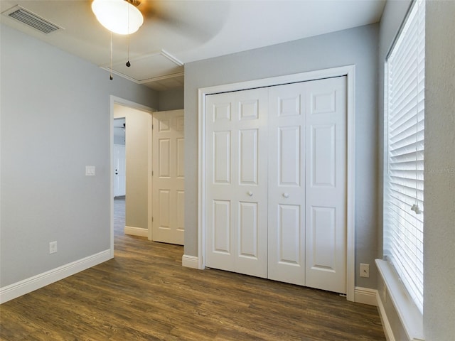 unfurnished bedroom featuring dark wood-type flooring, ceiling fan, and a closet