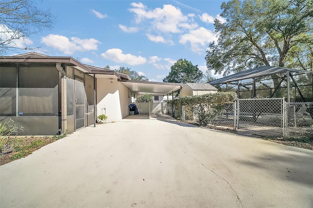 view of side of property with stucco siding, a gate, fence, a carport, and driveway