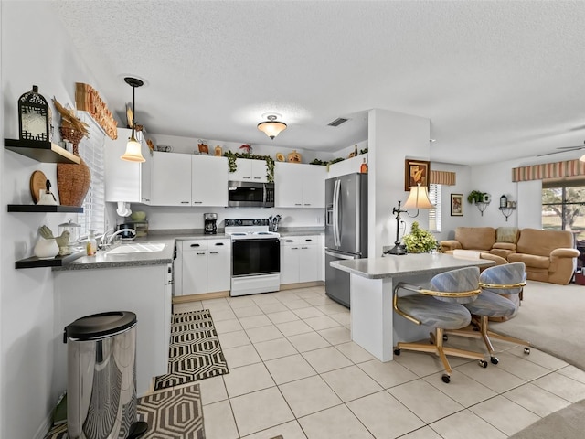 kitchen featuring hanging light fixtures, stainless steel appliances, sink, and white cabinets