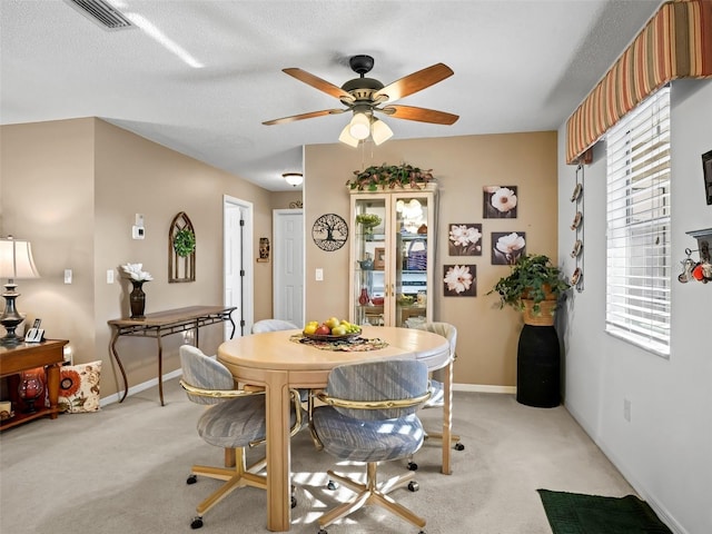 dining room featuring ceiling fan, light colored carpet, and a textured ceiling