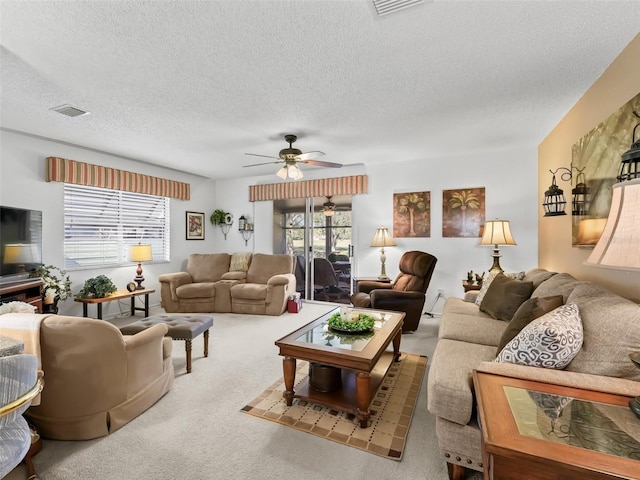 carpeted living room with ceiling fan and a textured ceiling