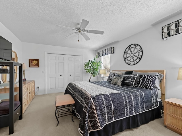 carpeted bedroom with ceiling fan, a closet, and a textured ceiling