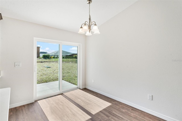 unfurnished dining area with an inviting chandelier and hardwood / wood-style flooring