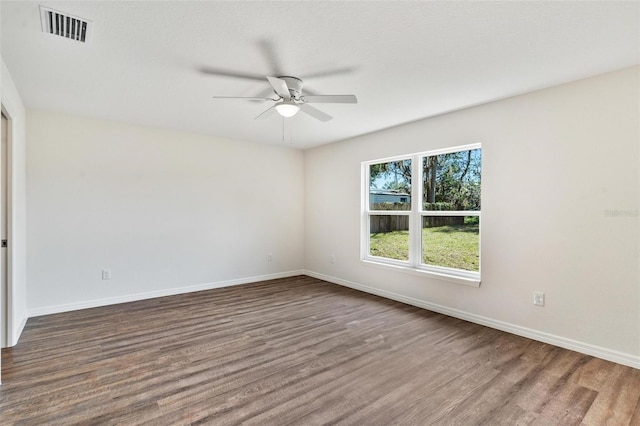 spare room with a ceiling fan, visible vents, baseboards, and wood finished floors