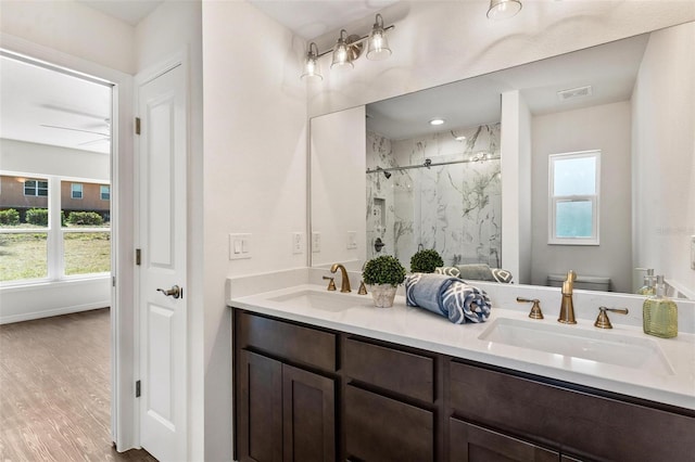 bathroom with vanity, a shower with shower door, plenty of natural light, and toilet