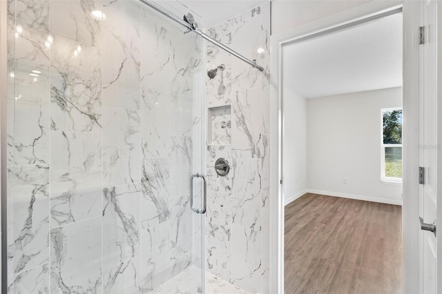 bathroom with a marble finish shower, baseboards, and wood finished floors