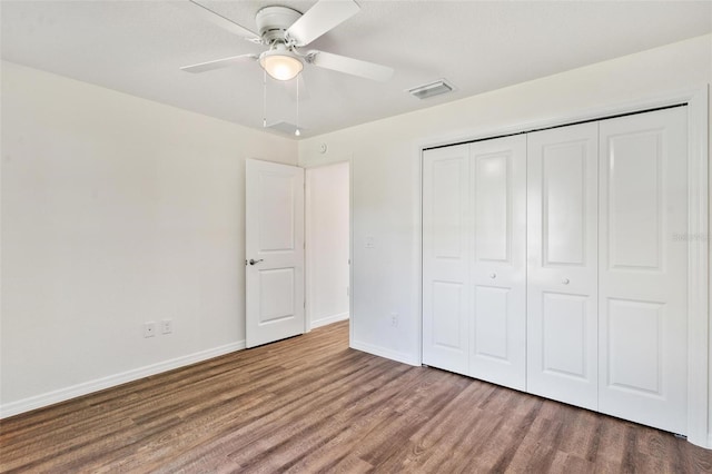 unfurnished bedroom featuring visible vents, baseboards, a ceiling fan, wood finished floors, and a closet