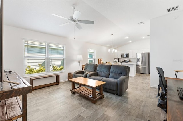 living room with ceiling fan with notable chandelier, vaulted ceiling, and light wood-type flooring