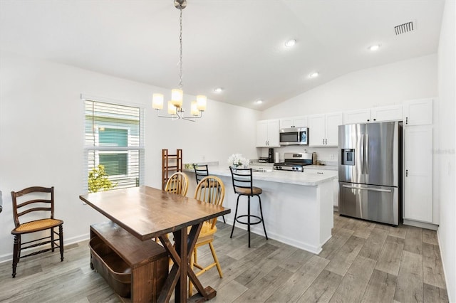 dining area featuring vaulted ceiling, a notable chandelier, and light wood-type flooring