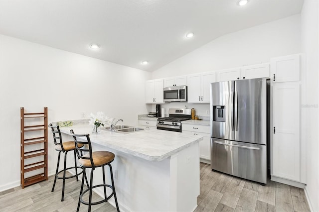 kitchen featuring sink, a breakfast bar area, kitchen peninsula, stainless steel appliances, and white cabinets