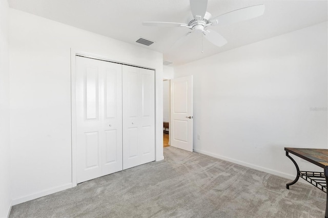 unfurnished bedroom featuring ceiling fan, a closet, and light carpet