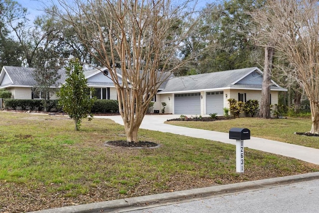 ranch-style home with brick siding, a front lawn, an attached garage, and driveway