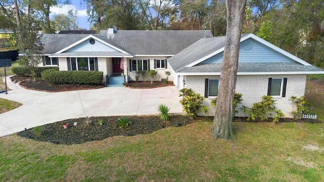 ranch-style house with a front yard, brick siding, roof with shingles, and a chimney