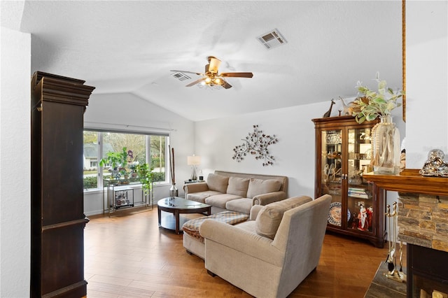 living room featuring lofted ceiling, wood finished floors, visible vents, and ceiling fan